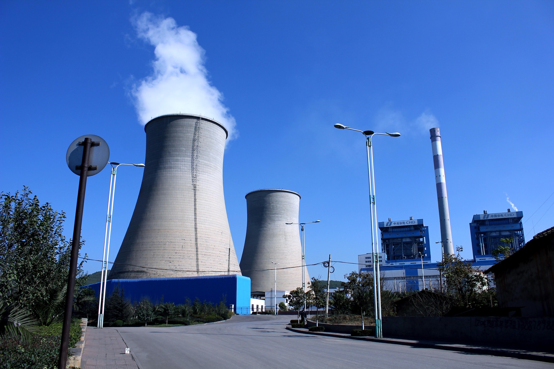 Cooling towers and a chimney at the Kunming II power plant, under a blue sky.